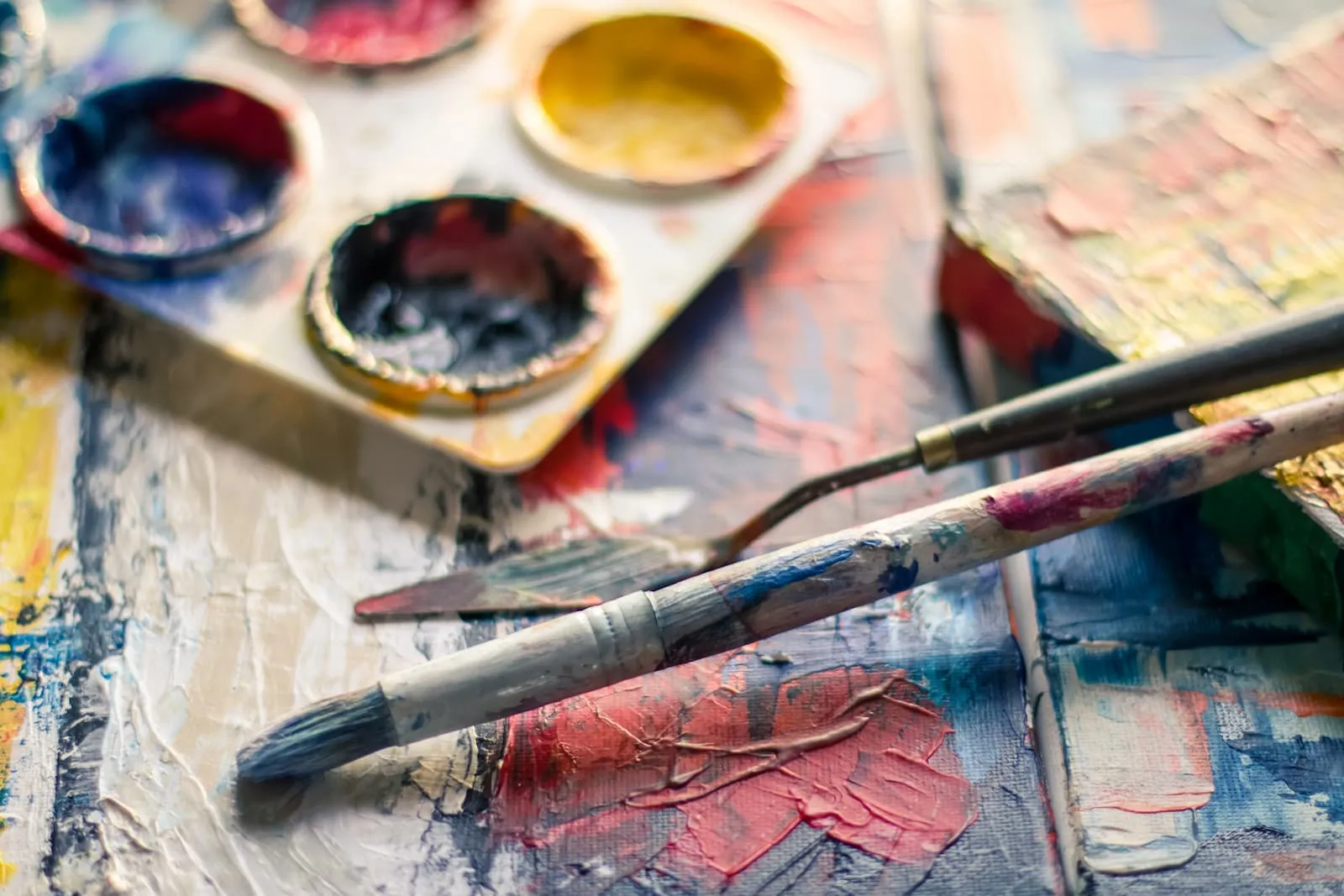 Brush and spatula on a brightly painted canvas.