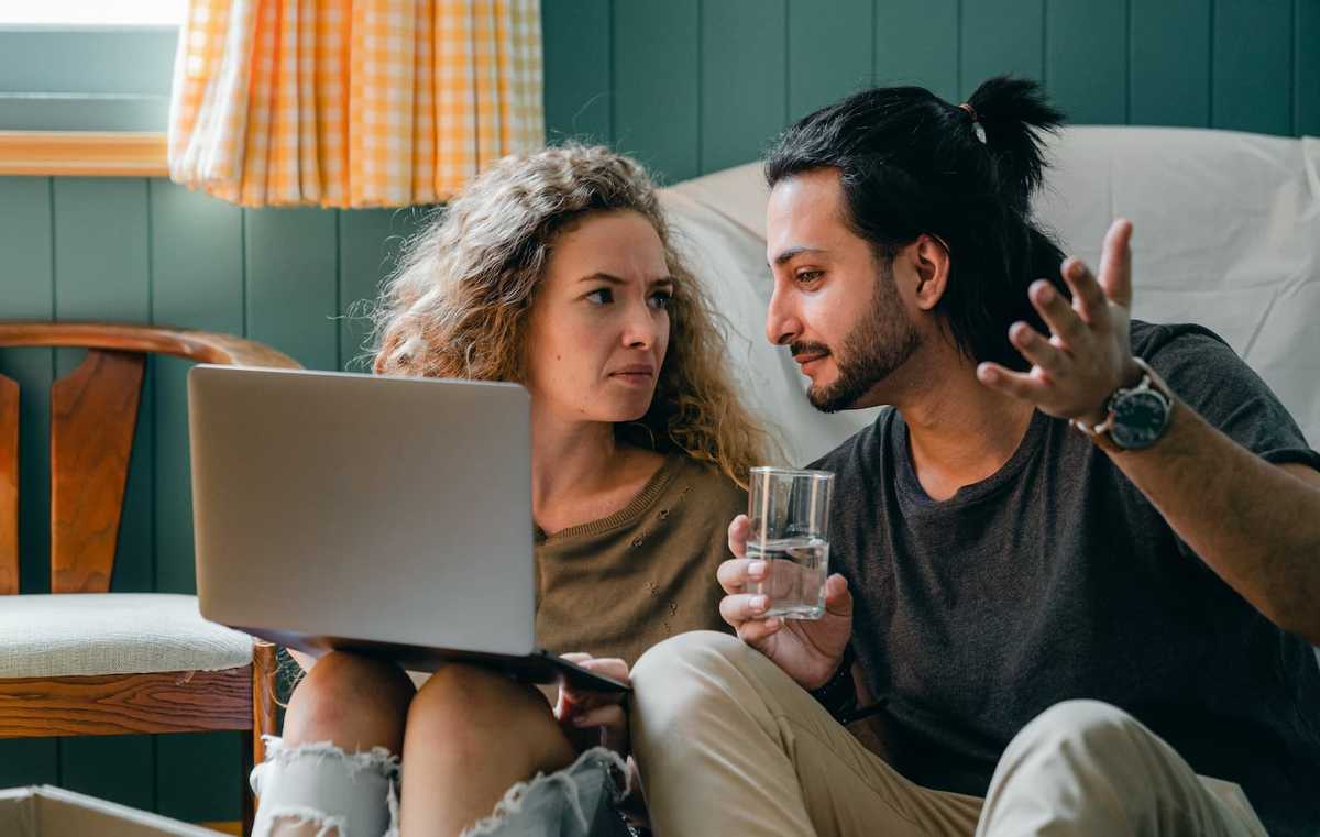 Zwei Personen besprechen den HTML-Code auf dem Laptop-Monitor vor ihnen.